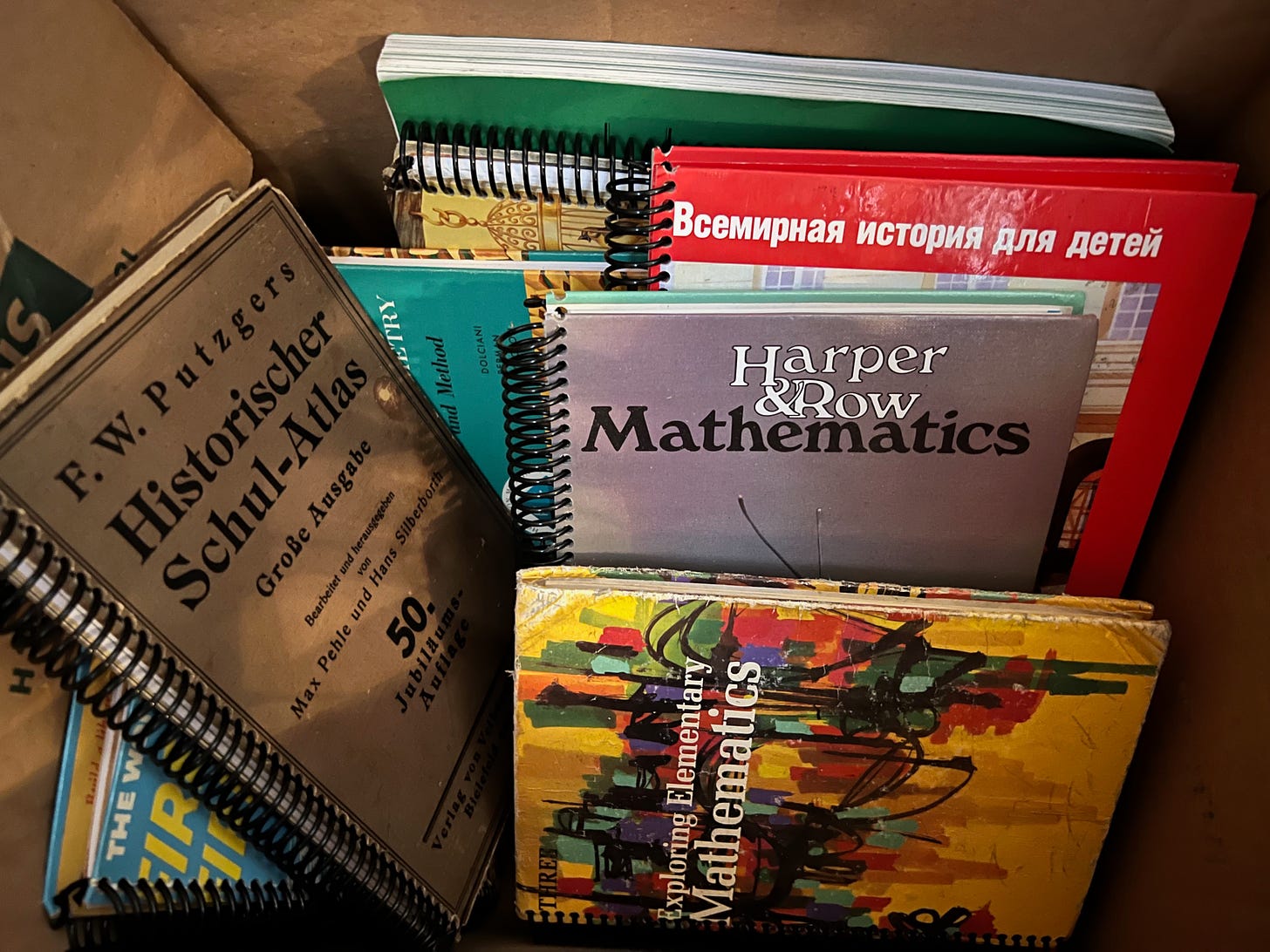 A box filled with what looks like old textbooks, mostly mathematics textbooks, spiral-bound. They are actually repurposed books filled with blank pages to write on.