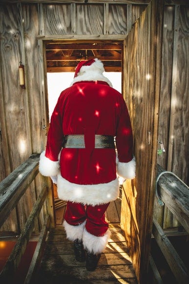 A shot of Santa walking out of the reindeer barn, but it looks like a comedian about to walk on stage and perform a live special