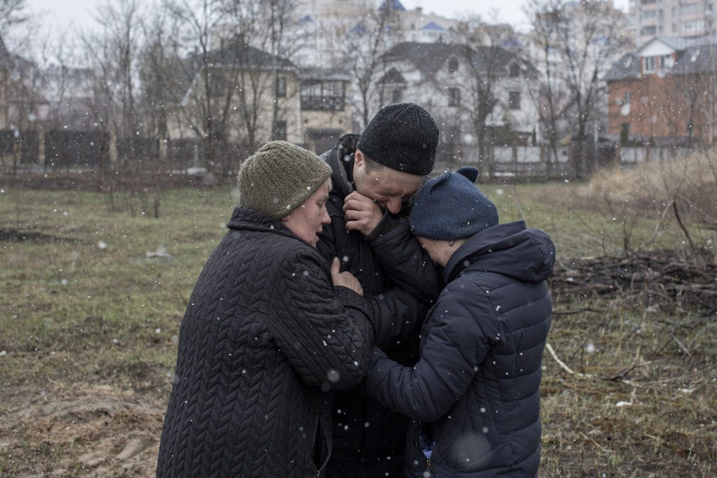A family grieve for a missing relative in front of a mass grave in the town of Bucha, on the outskirts of Kyiv, after the Ukrainian army secured the area following the withdrawal of the Russian army from the Kyiv region on previous days, Bucha, Ukraine on April 03, 2022. (Photo by Narciso Contreras/Anadolu Agency via Getty Images)