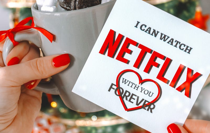 A photo of a a woman’s hands holding a coffee cup and a card that reads, “I can watch Netflix with you forever,” which is ironic because you can’t watch forever unless you pay forever.