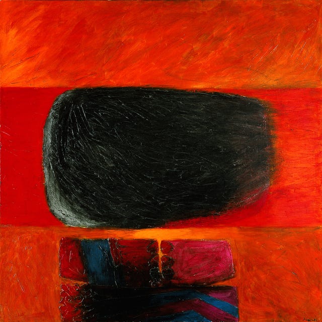 A black blotch of irregular shape floats against a background of strong red and orange tones.  Below, a piece of what appears to be pre-Colombian art is reflected against the bright red scenery. The piece is long and cherry-colored with blue stripes; it has a rough texture with a crevice in the center.