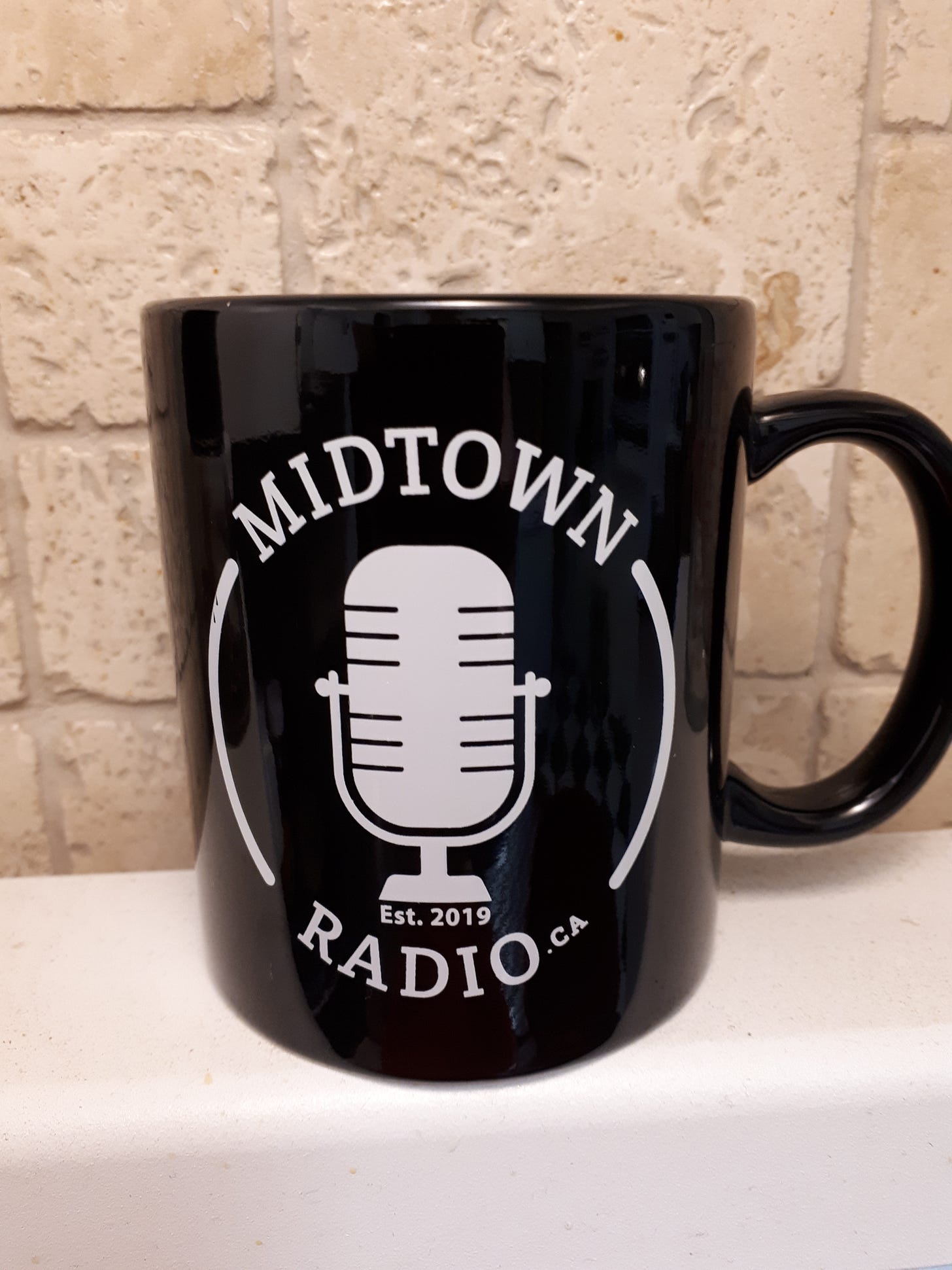 Black mug with white image of an old style radio microphone and white text says Midtown Radio.