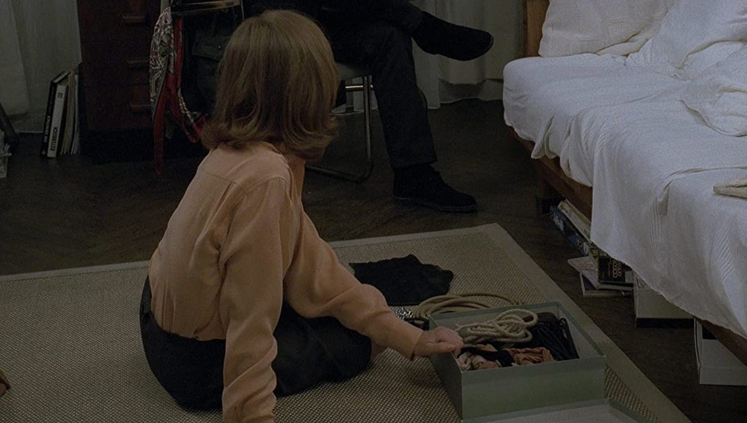 Isabelle Huppert in "The Piano Teacher" sitting on her bedroom floor with a box of fetish paraphernalia.