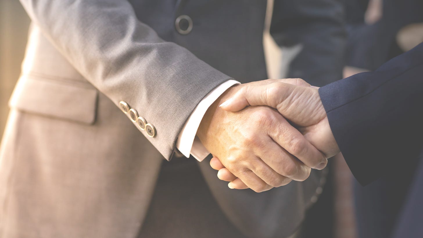 handshaking between two people in suits
