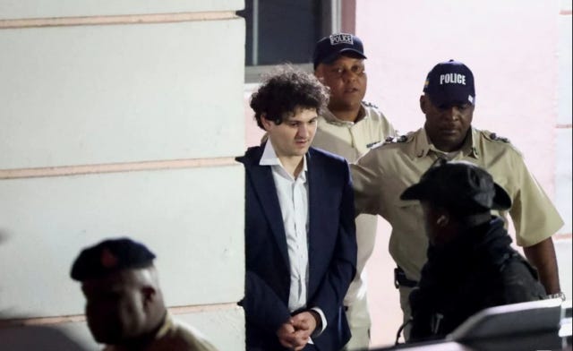 Sam Bankman-Fried, being led from a Bahamian courthouse with his hands handcuffed in front of him.