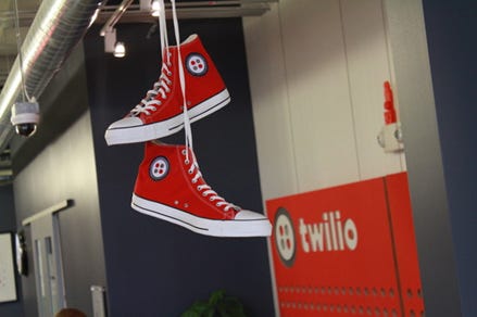 a pair of red converse hanging and twilio is written behind them on half painted red wall