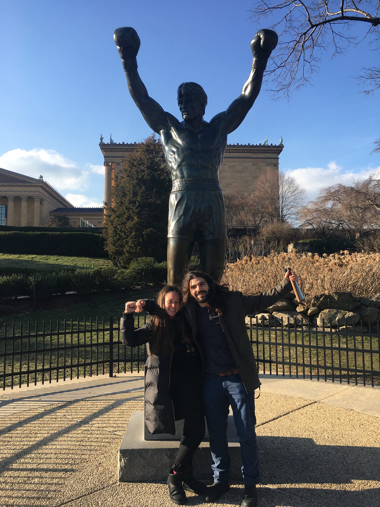 anthony and kelly stand in front of the rocky statue in philly