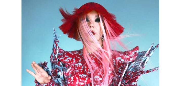 Bjork in a red wig over pink hair, and a brighly colored angular costume