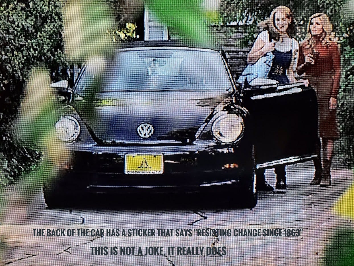 A zoomed in shot of Bren's VW Beetle with a Gadsden flag placard on the front, captioned "the back of the car has a sticker that says 'resisting change since 1863, this is not a joke, it really does"