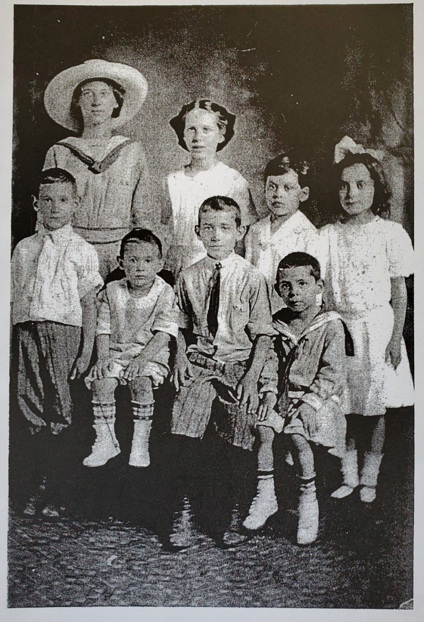 A black and white photo of eight children in typical early 20th century dress. 