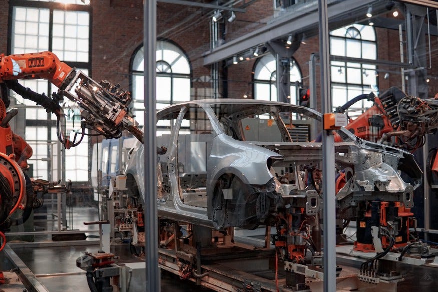 Car being assembled by robots in a factory. Software Product Development Is Not A Production Line | How coding factories are born by Zaheer Abzal | medium.com/@zaheerabzal | Use lean principles to emerge software development practices.