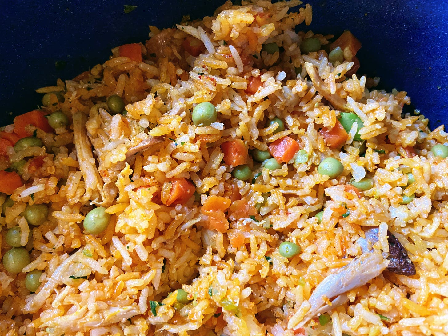 Close-up of Costa Rican dish arroz con pollo, with orange rice, vegetables, chicken mixed together