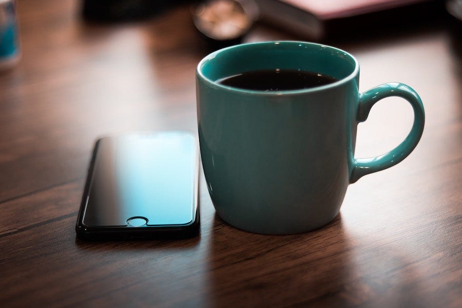 iPhone and coffee cup on a table