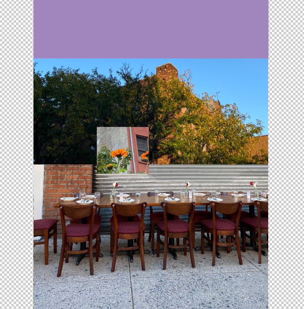 A long, wooden dining chair for a restaurant sits outside on the sidewalk. Plates, silverware, and flowers are arranged neatly on the table, but no one is seated at any of the 13 visible chairs. Above is a cropped image of a widow and an orange flower. Behind the window is the top of a residential brick building, obstructed by a large tree. The sun hits part of the building’s facade and several of the tree’s leaves. The sky is a bright, cloudless blue behind the tree top and building. 