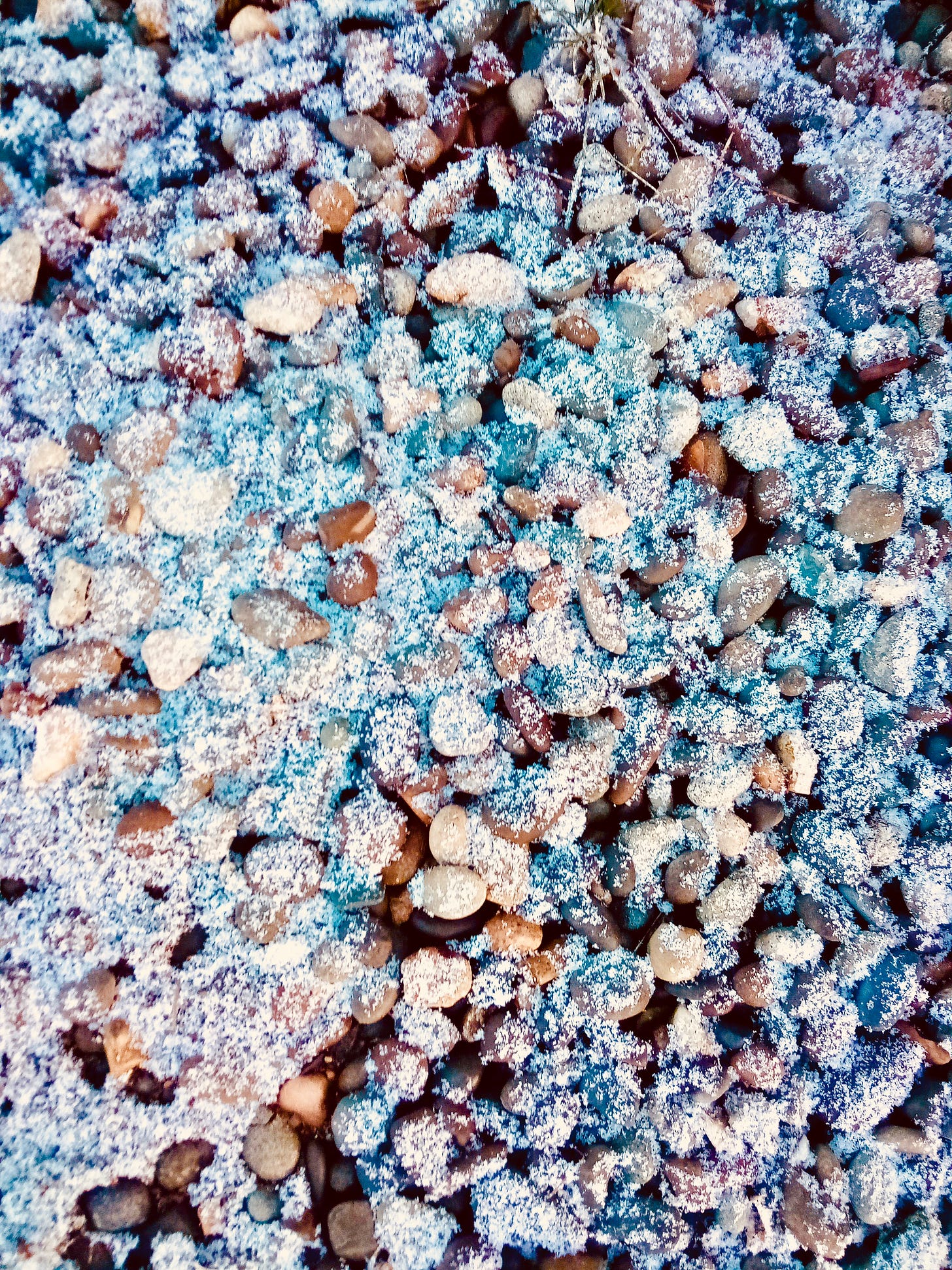 Photo of colorful pebbles under a dusting of snow.