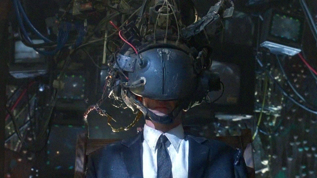 Keanu Reeves in a suit and tie with a ridiculous cyberpunk VR headset