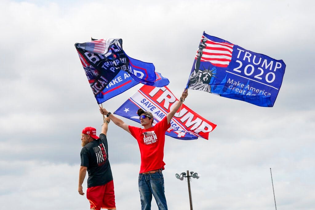 Trump supporters wave flags as they wait in line outside a political rally at Wilkes-Barre, Pennsylvania.