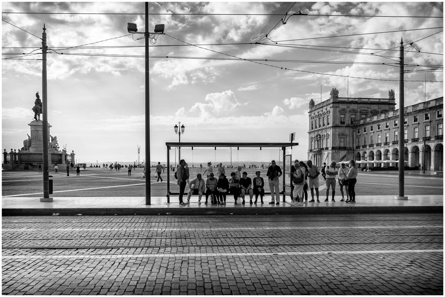 wide shot in black and white of people waiting at a trolley stop