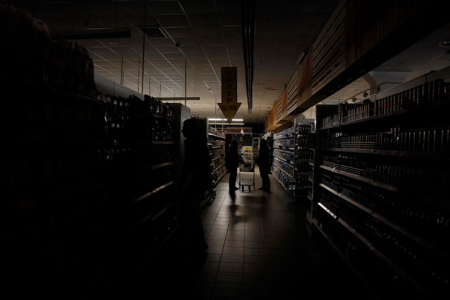 Two people shop in a dark supermarket during a power outage.