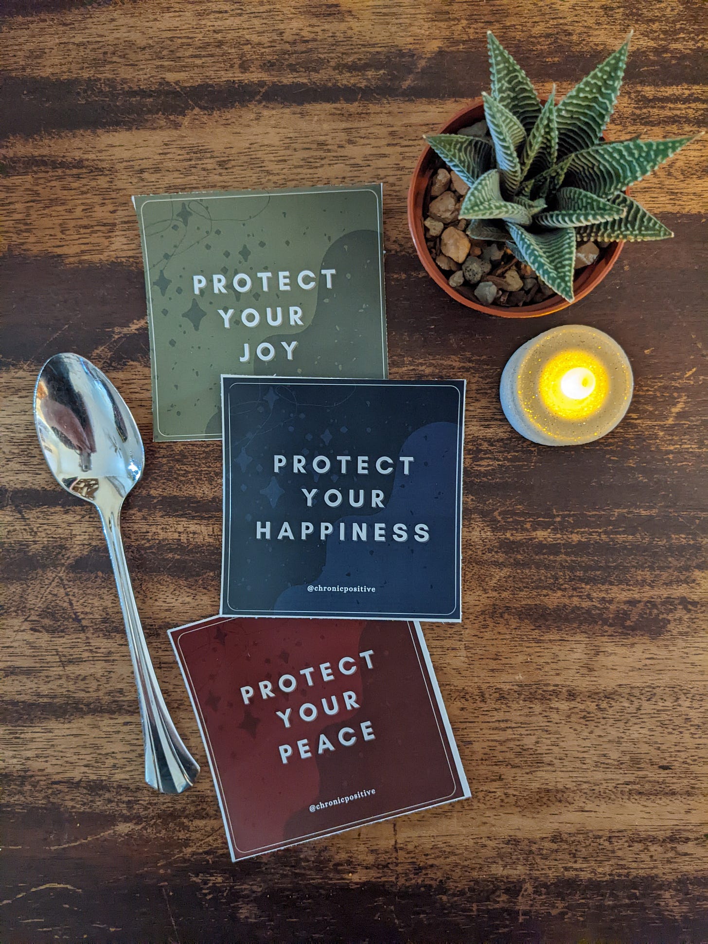 A green sticker that says "protect your joy," a navy sticker that says "protect your happiness," and a burgundy sticker that says "protect your peace."