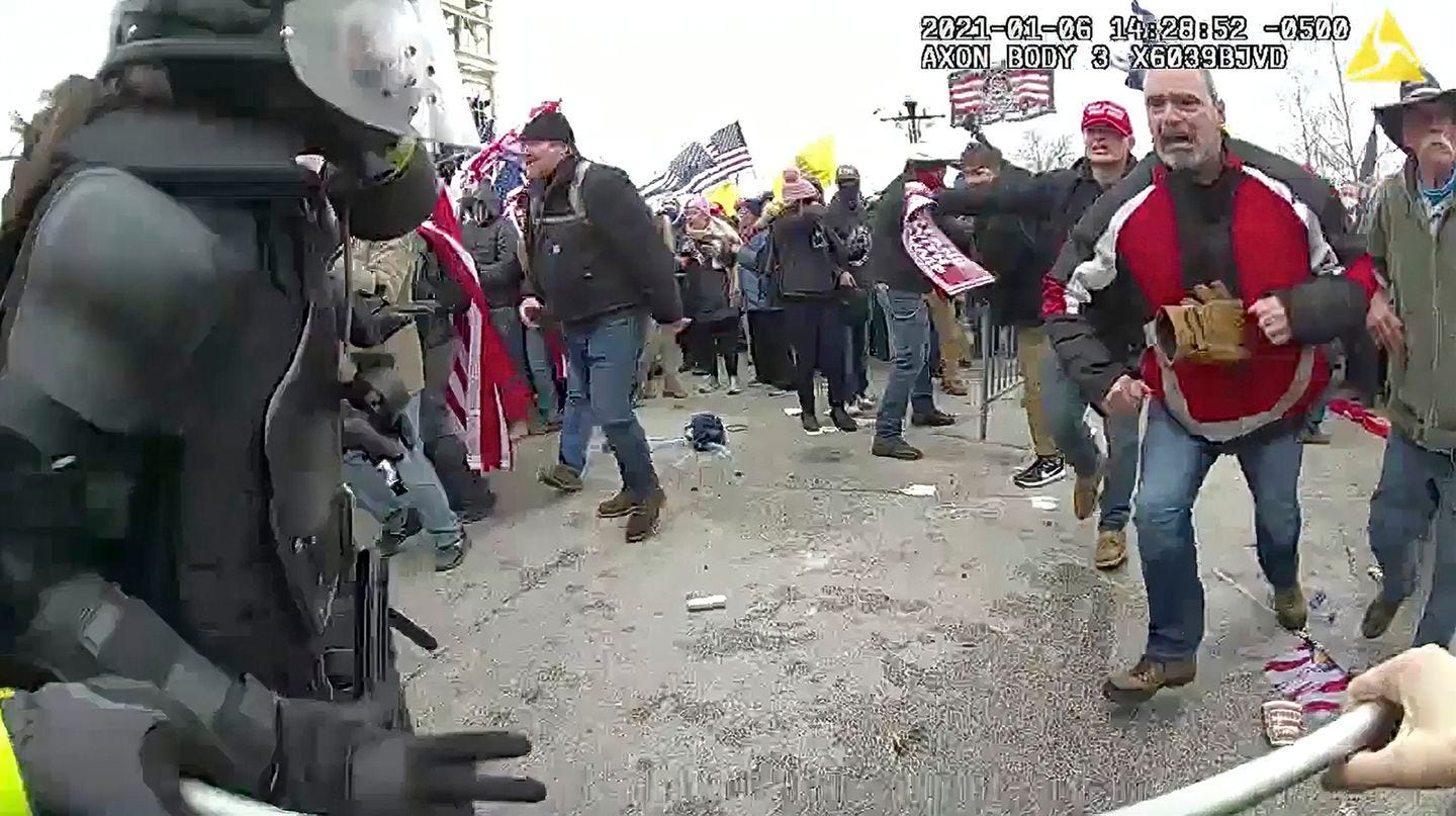 This still frame from Metropolitan Police Department body worn camera video shows Thomas Webster, in red jacket, at a barricade line at on the west front of the U.S. Capitol on Jan. 6, 2021, in Washington. Webster, a Marine Corps veteran and retired New York City Police Department Officer, is accused of assaulting an MPD officer with a flagpole. A number of law enforcement officers were assaulted while attempting to prevent rioters from entering the U.S. Capitol. (Metropolitan Police Department via AP)