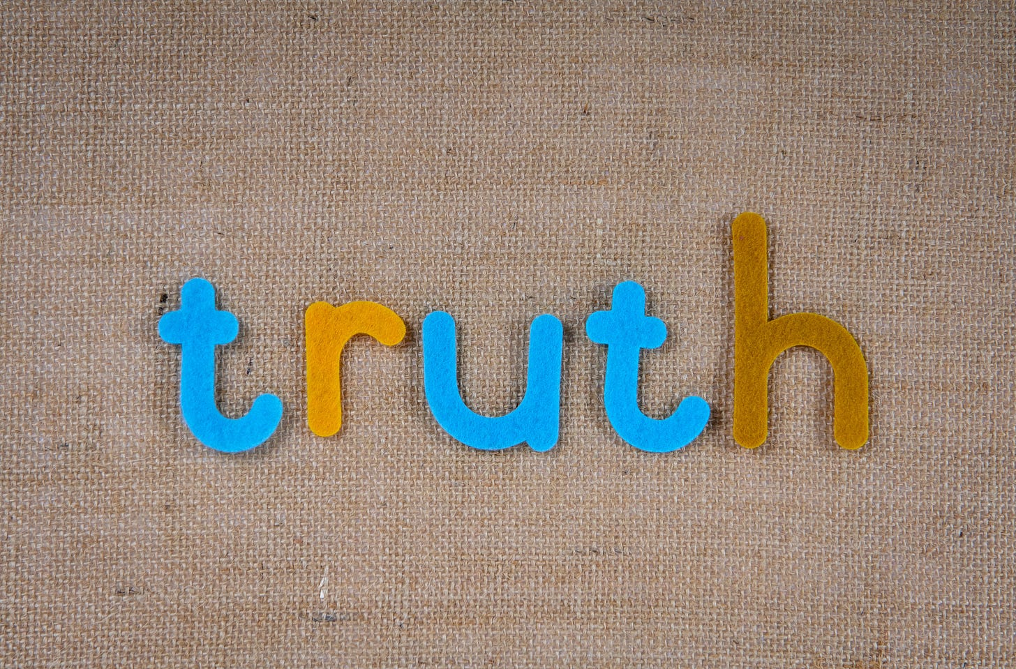 the word "truth" in letters cut out of fabric against a canvas background