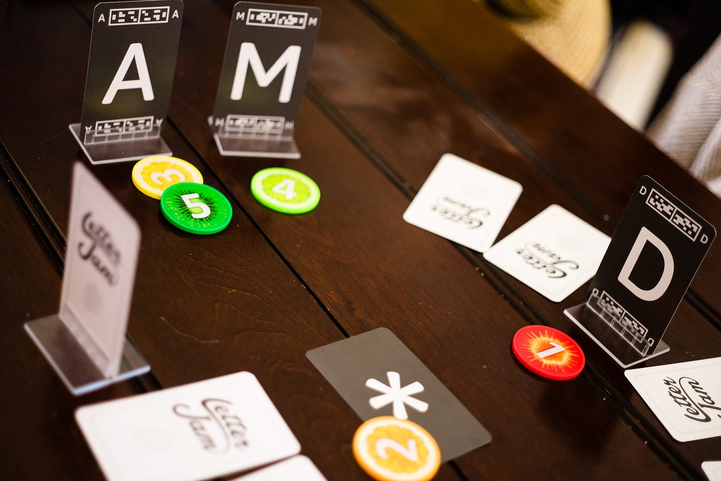 The board game Letter Jam being played at a table. The letters “A”, “M” and “D” are visible.
