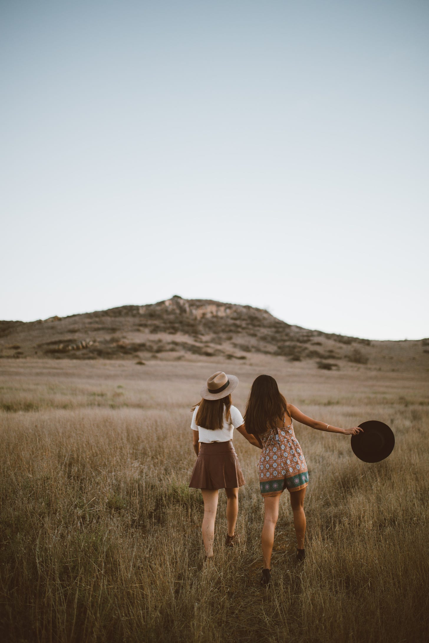 Two girls walking through the fields towards a hill