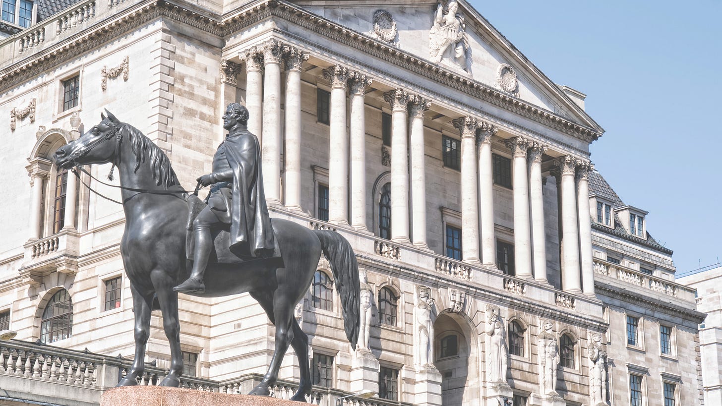 a sideview monument of a man on a horse in front of an old building with corinthian columns