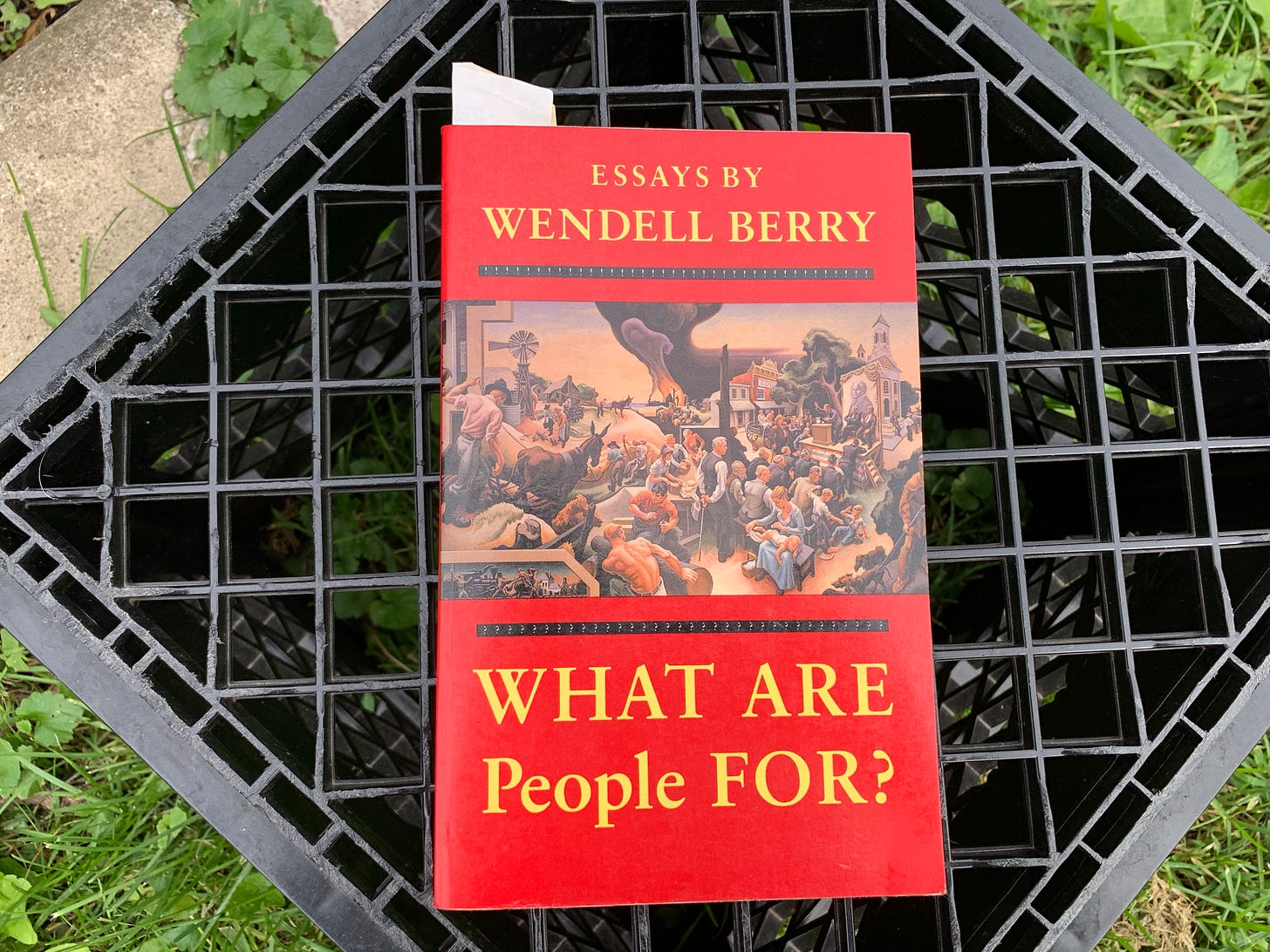 A milk crate with Wendell Berry's "What Are People FOR?" on top