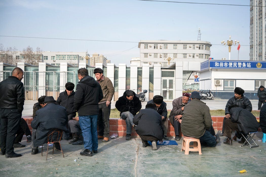 和田主广场警务站附近的维吾尔人。活动人士指控中国政府对穆斯林实施大规模监控、酷刑和强制绝育等虐待行为。