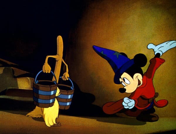 Mickey Mouse dressed as a wizard, looking at a walking broom carrying two buckets.