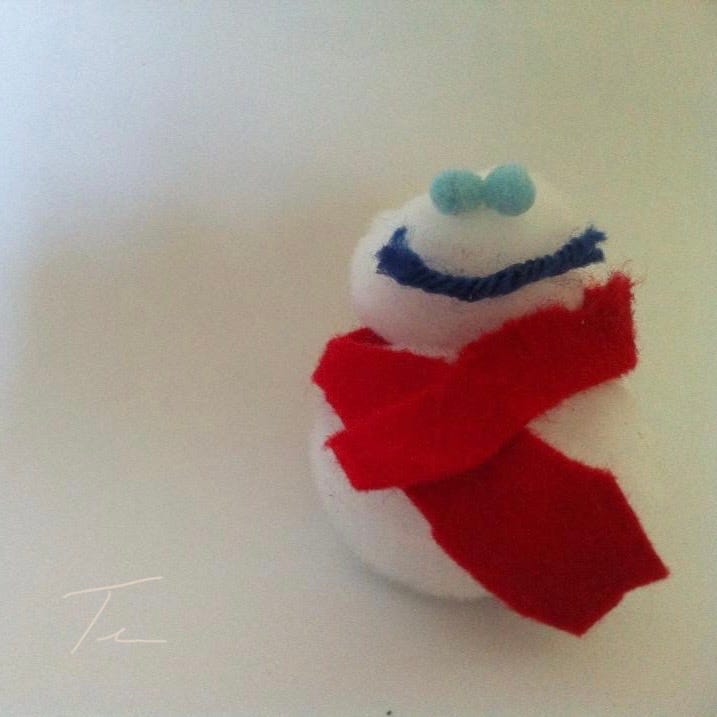 Pom-pom snowman with felt scarf and a big yarn smile.