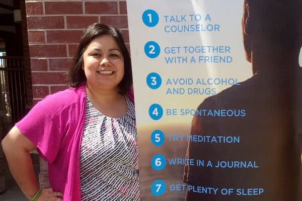 Alma Lopez, a school counselor at Livingston Middle School and the district’s counselor coordinator, alongside a banner about mental health in Livingston, Calif.