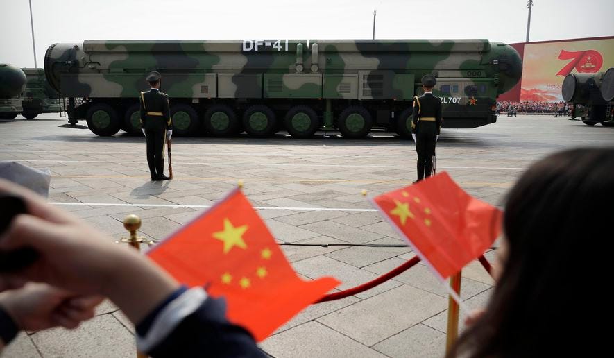 Spectators wave Chinese flags as military vehicles carrying DF-41 ballistic missiles roll during a parade to commemorate the 70th anniversary of the founding of Communist China in Beijing, Oct. 1, 2019. China’s military buildup has triggered unease across Asia and was the driving factor behind the recent formation of a three-way U.S., Britain and Australia security pact focused on the region, according to President Biden’s top national security adviser for the Indo-Pacific. (AP Photo/Mark Schiefelbein) ** FILE **