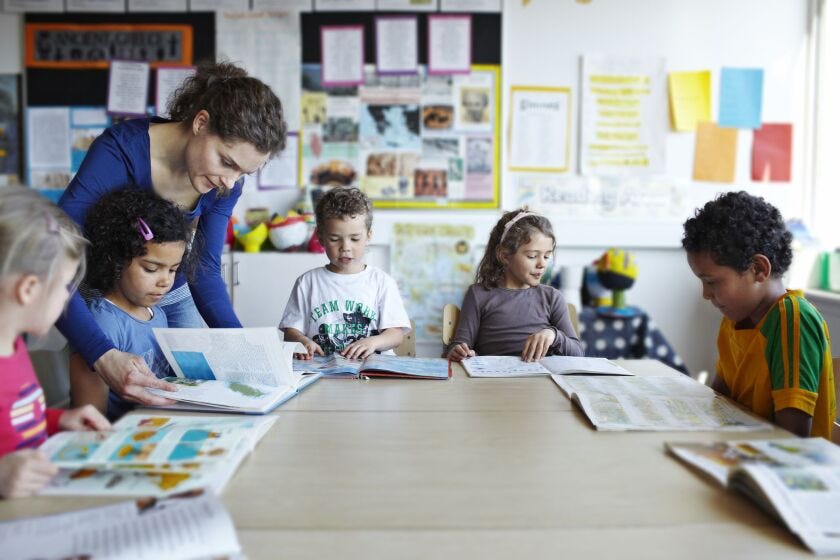 A teacher with young students in the classroom.