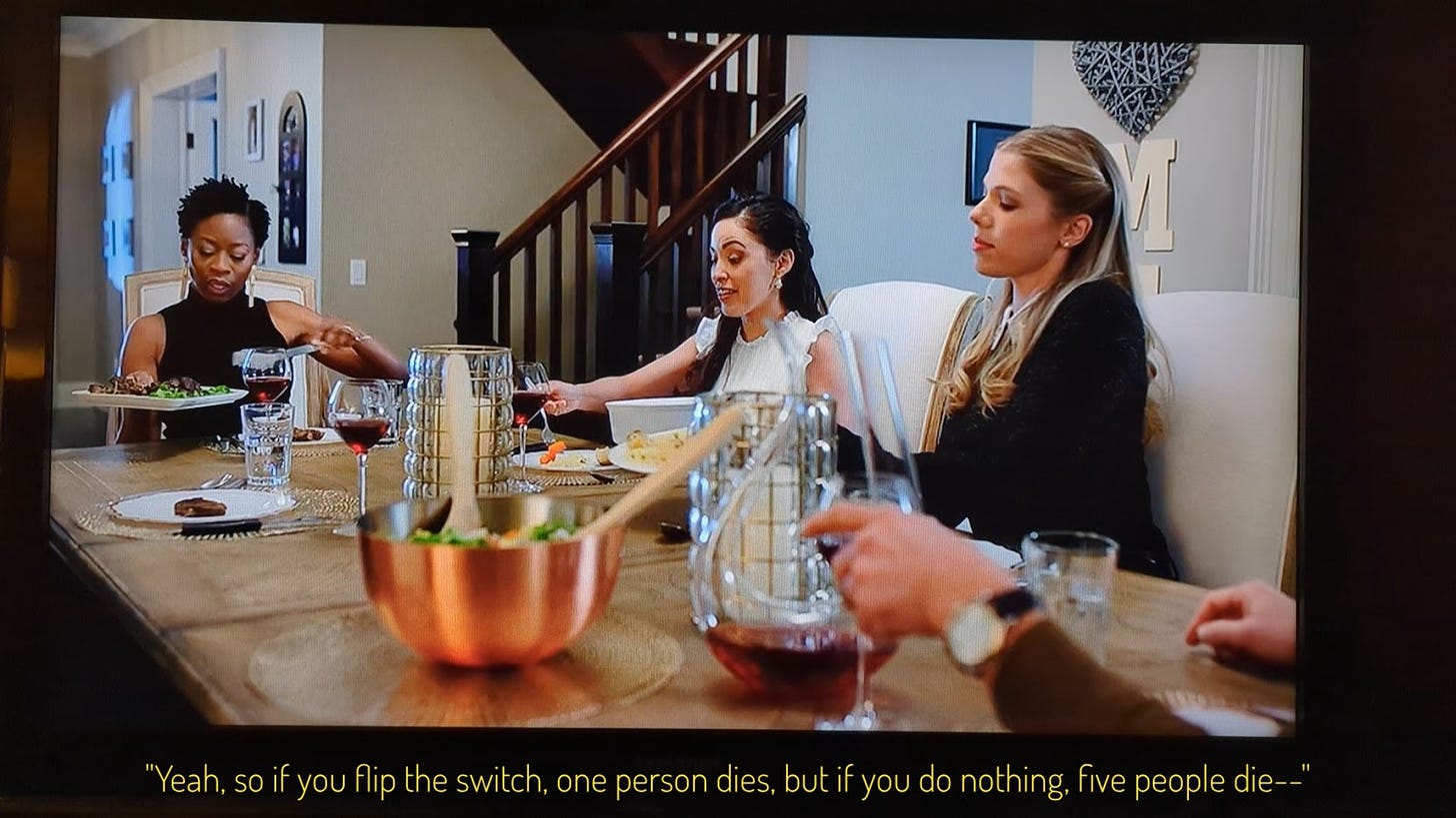 Victoria, Luna, and Claire at the dinner table, Luna is talking, captioned "Yeah so if you flip the switch, one person dies, but if you do nothing five people die--"