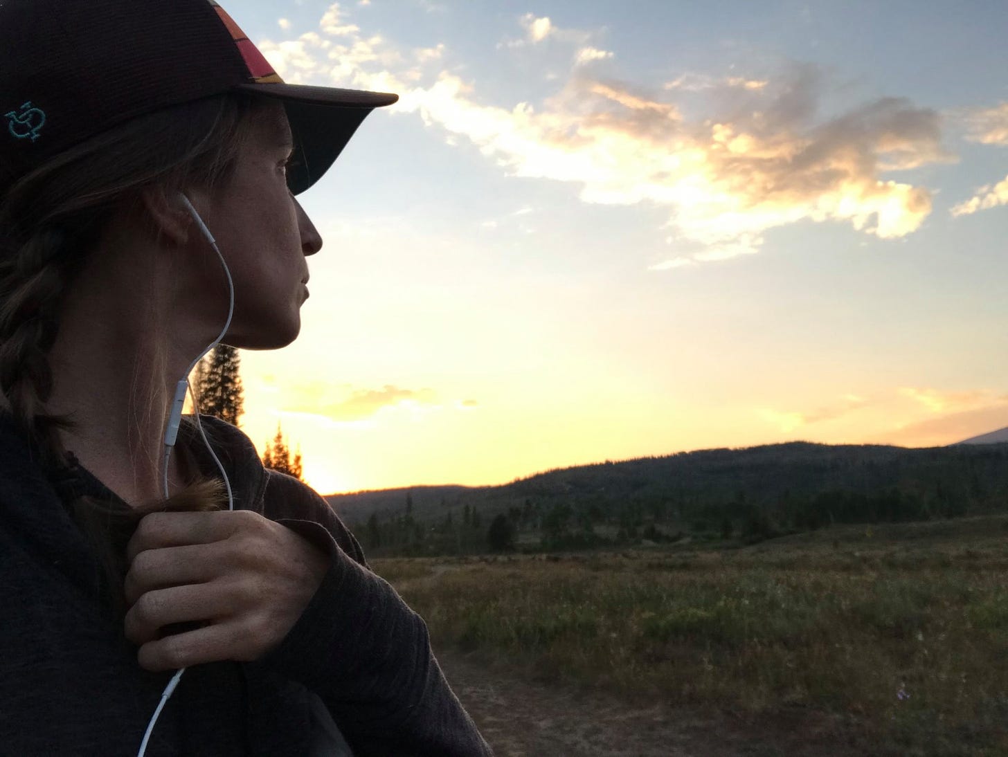 selfie of the author, looking over her shoulder to the sunset behind her