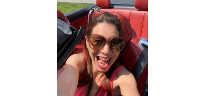 a woman in a car with an open smile taking a selfie