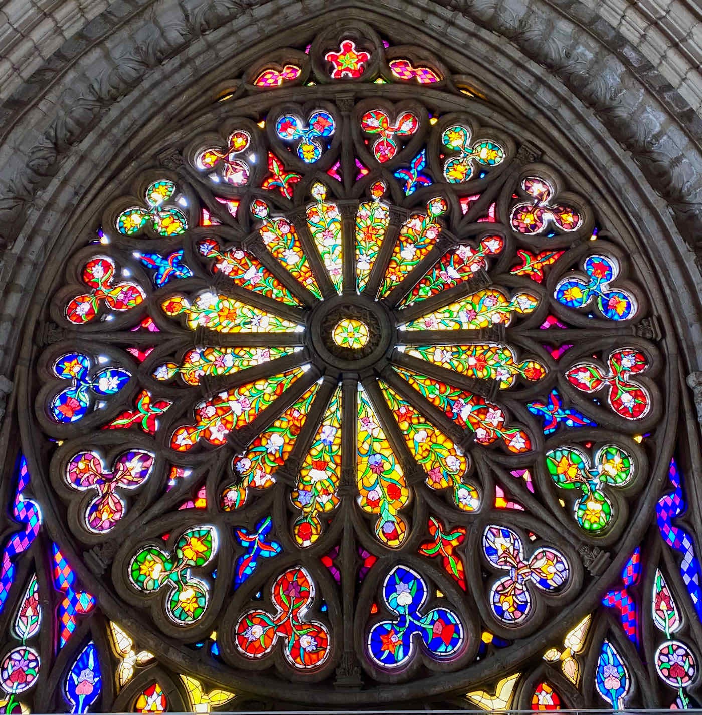Rose window featuring orchids in various shades of yellow, red, green, blue, and orange