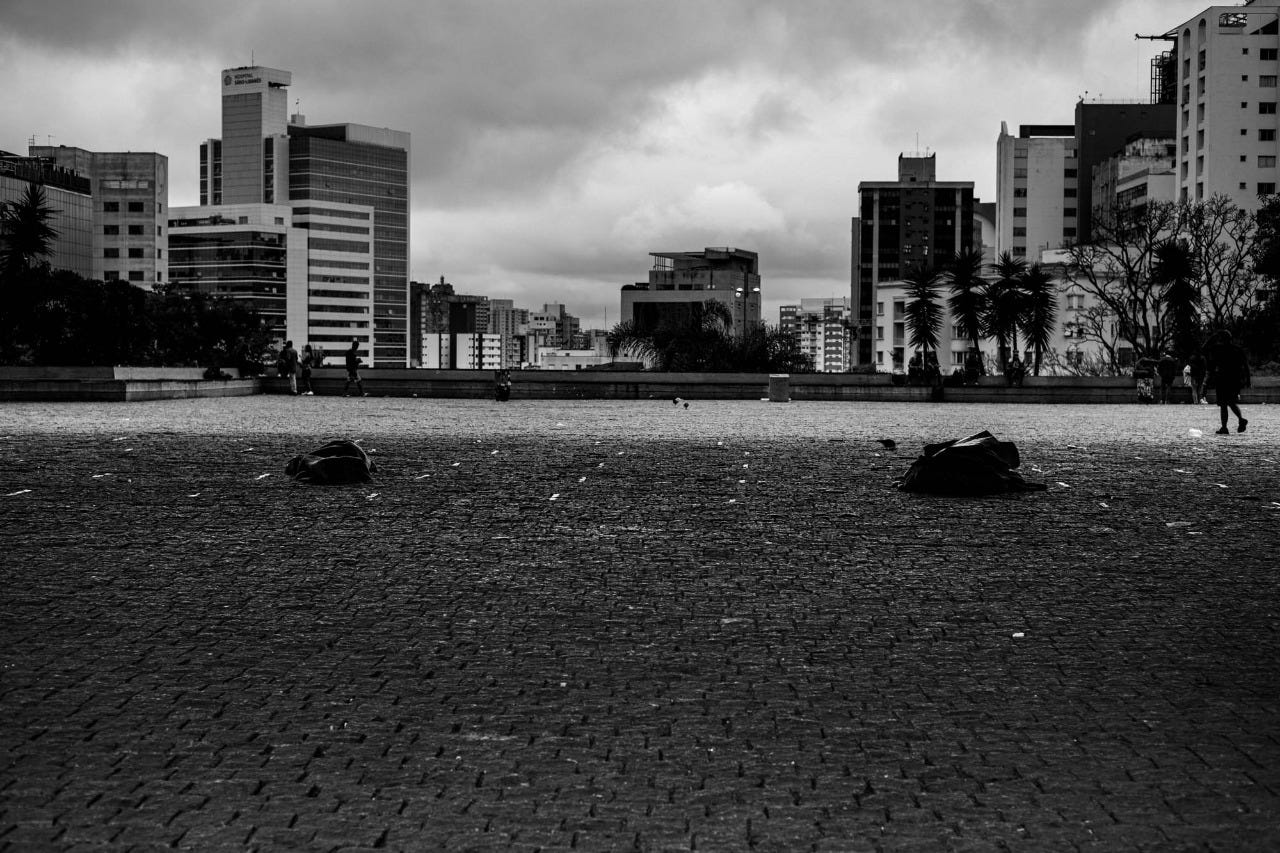 Imagem em preto e branco mostra vão do MASP, na Avenida Paulista, onde pessoas dormem no chão
