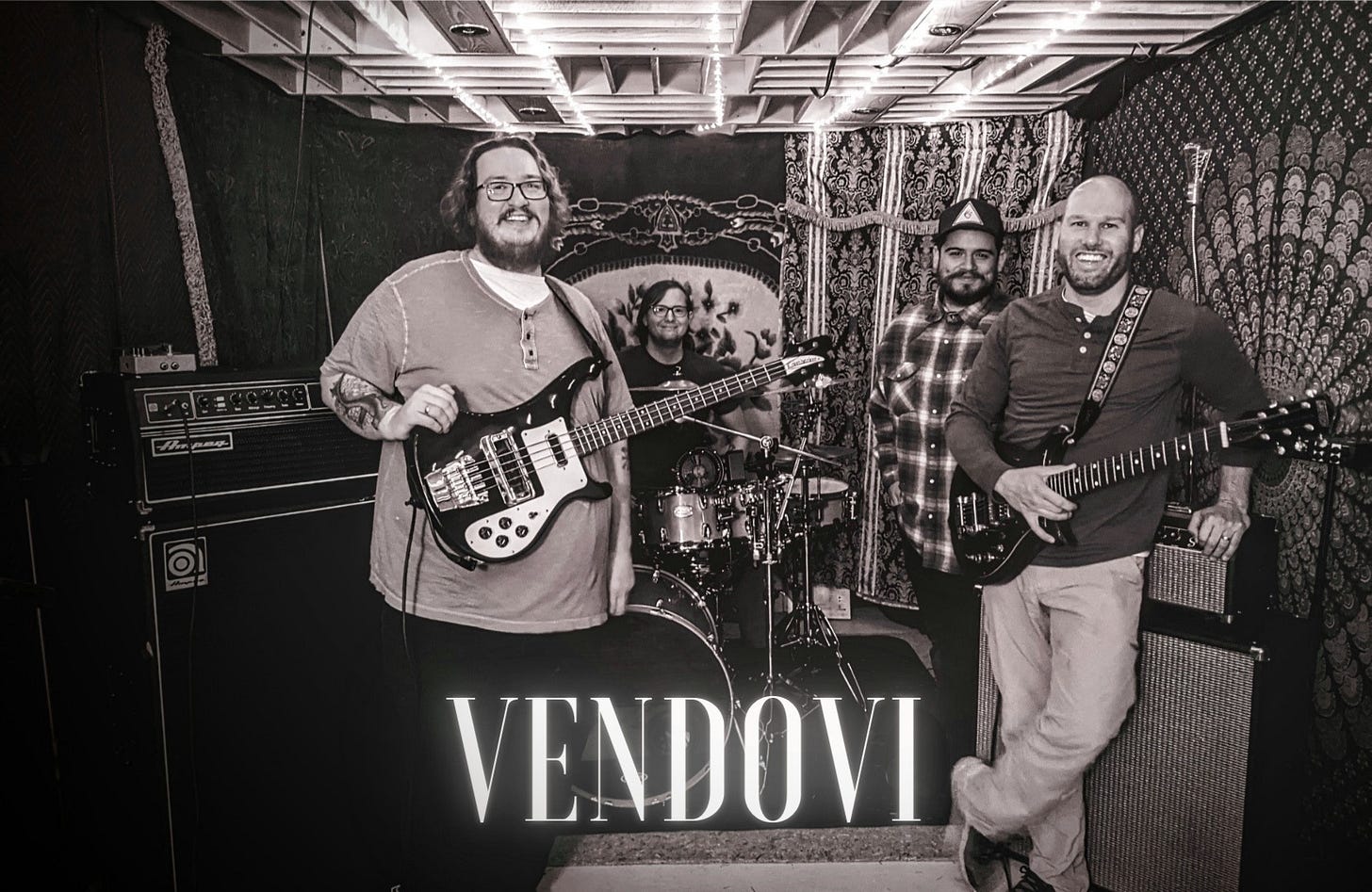 a black and white photo of four musicians in a practice space