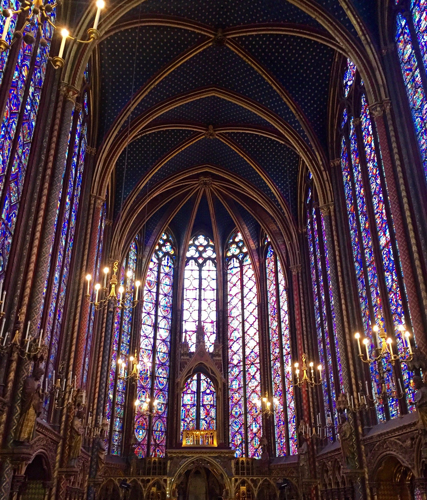 cathedral with walls of stained glass and gold arches. the ceiling is dark blue with gold stars, and the windows give off a purple glow