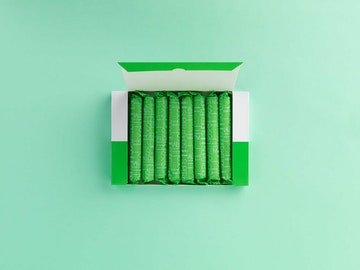 green box of plastic free tampons on a light green background