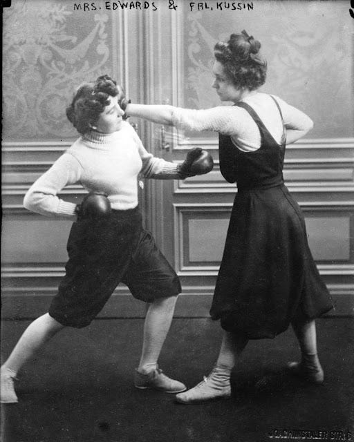 Two 19th Century women boxing in an Edwardian drawing room