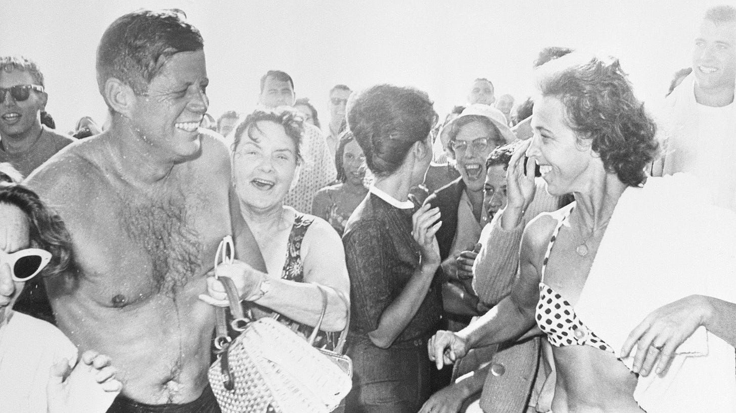 John F Kennedy with lots of happy women