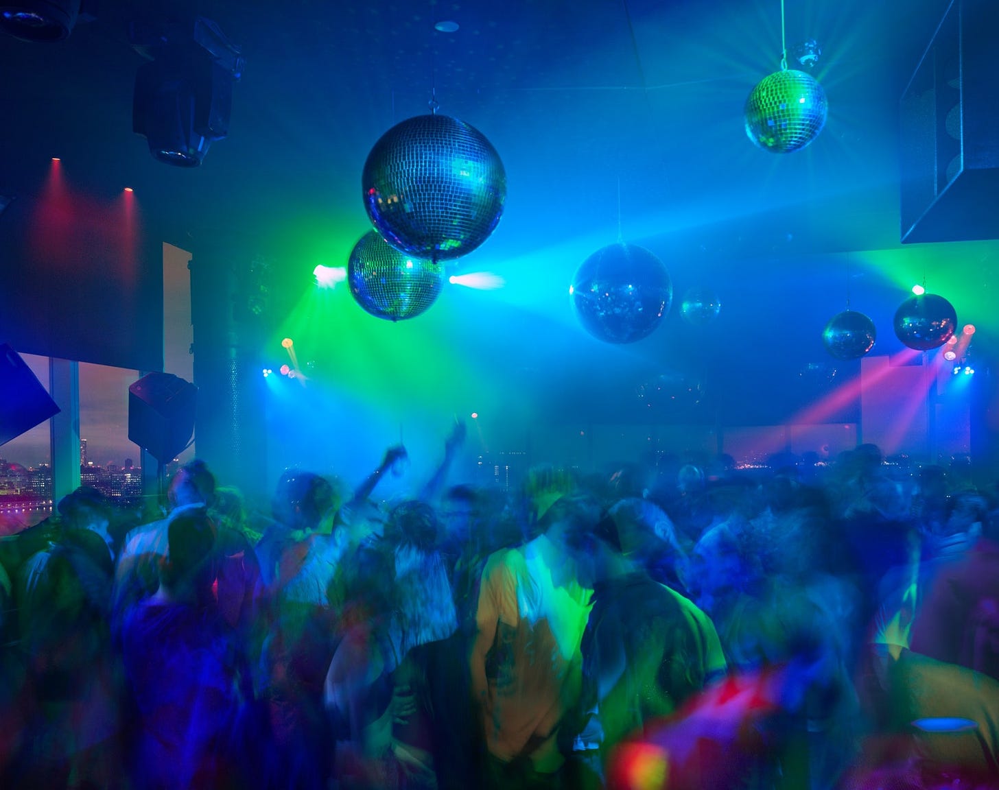 Blurry figures under disco balls at a night club