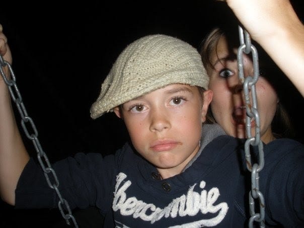 Me, a white kid at age twelve, looking eight, wearing a blue Abercrombie sweatshirt and a grey knitted cap-beret thing. I'm sitting on a swing.