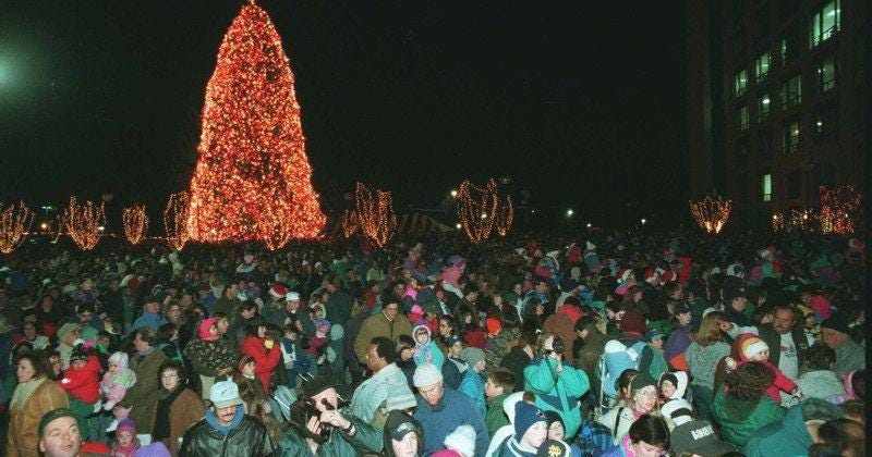 large Christmas tree aglow with lights and surrounded by a bundled-up crowd
