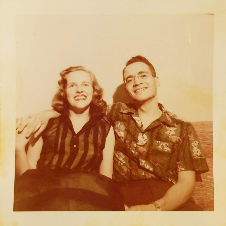 A man and a woman ca. the late 1950s, sitting together holding hands. They are both smiling. The color tone is sepia.
